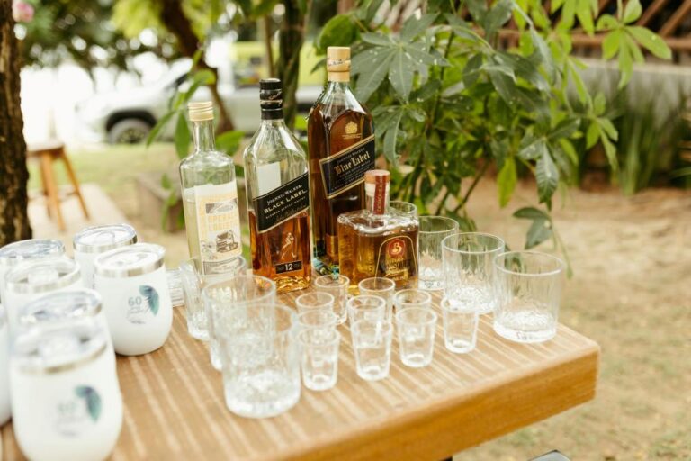 An elegant outdoor table setting with whiskey bottles and glasses for a tasting event.
